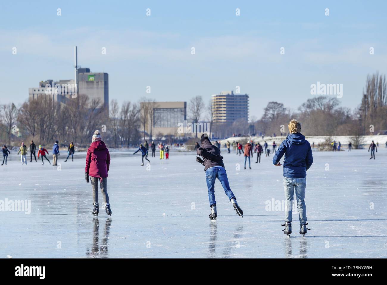 Wagenignen, Niederlande - 13. Februar 2021: Eisläufer haben Spaß in der Sonne auf gefrorenen Auen am Rhein in Holland Stockfoto