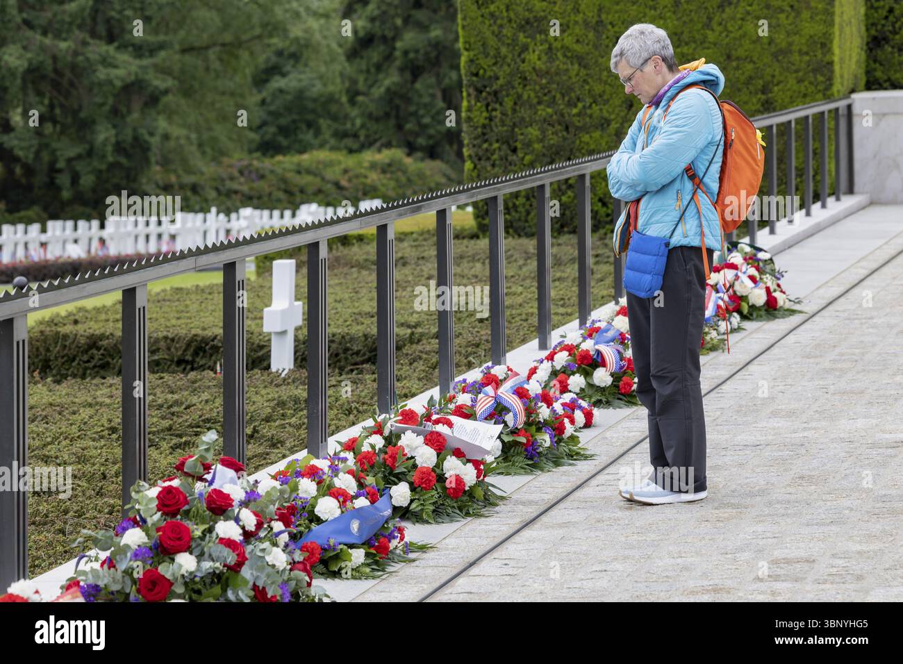Eine Frau, die vor Blumenarrangements auf einem Friedhof, dem Luxemburger amerikanischen Friedhof und Memoria, Luxemburg, Großherzogtum Luxemburg, in Gedanken war Stockfoto