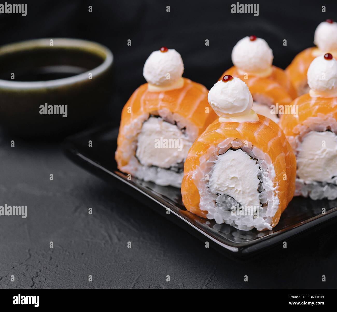 Stillleben, Lachs-Sushi mit Reis auf schwarzem Teller Stockfoto