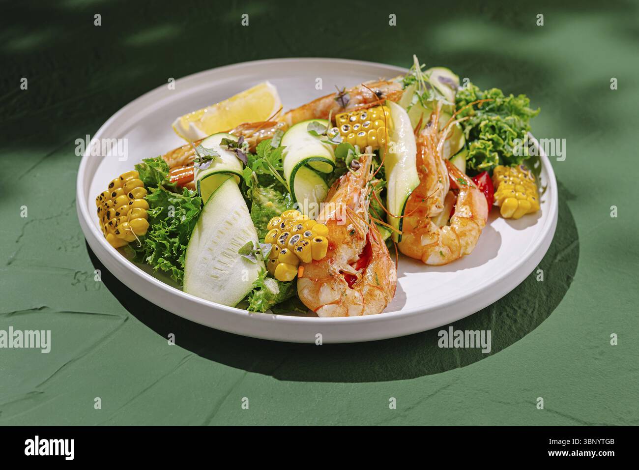 Food still Life, Eine lebendige Garnelenplatte mit großen Garnelen kombiniert mit farbenfrohem Gemüse, einschließlich Mais, Gurke und Salat, garniert mit Stockfoto