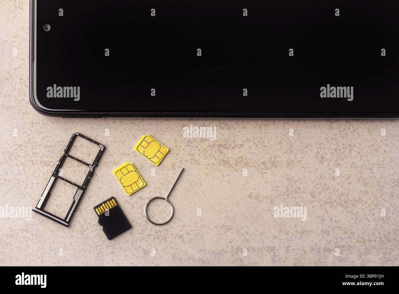 Smartphone und freie Steckplätze für Nano-SIM-Karten, zwei Nano-SIM-Karten, Micro-SD-Laufwerk und Metallschlüssel auf grauem Hintergrund Stockfoto