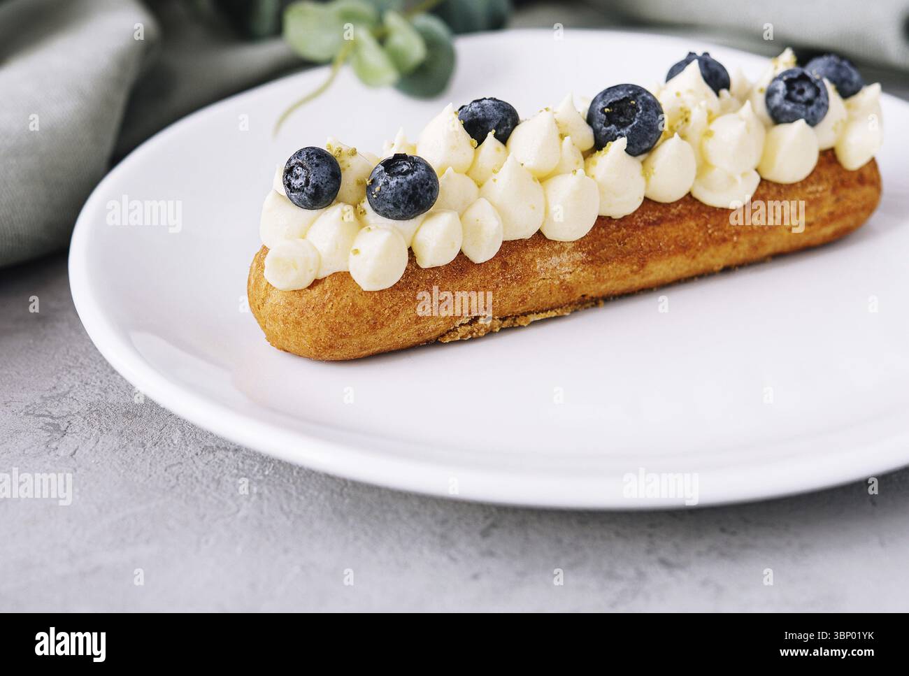 Essen Stillleben, leckere französische Eclairs mit Sahne und frischen Beeren Stockfoto
