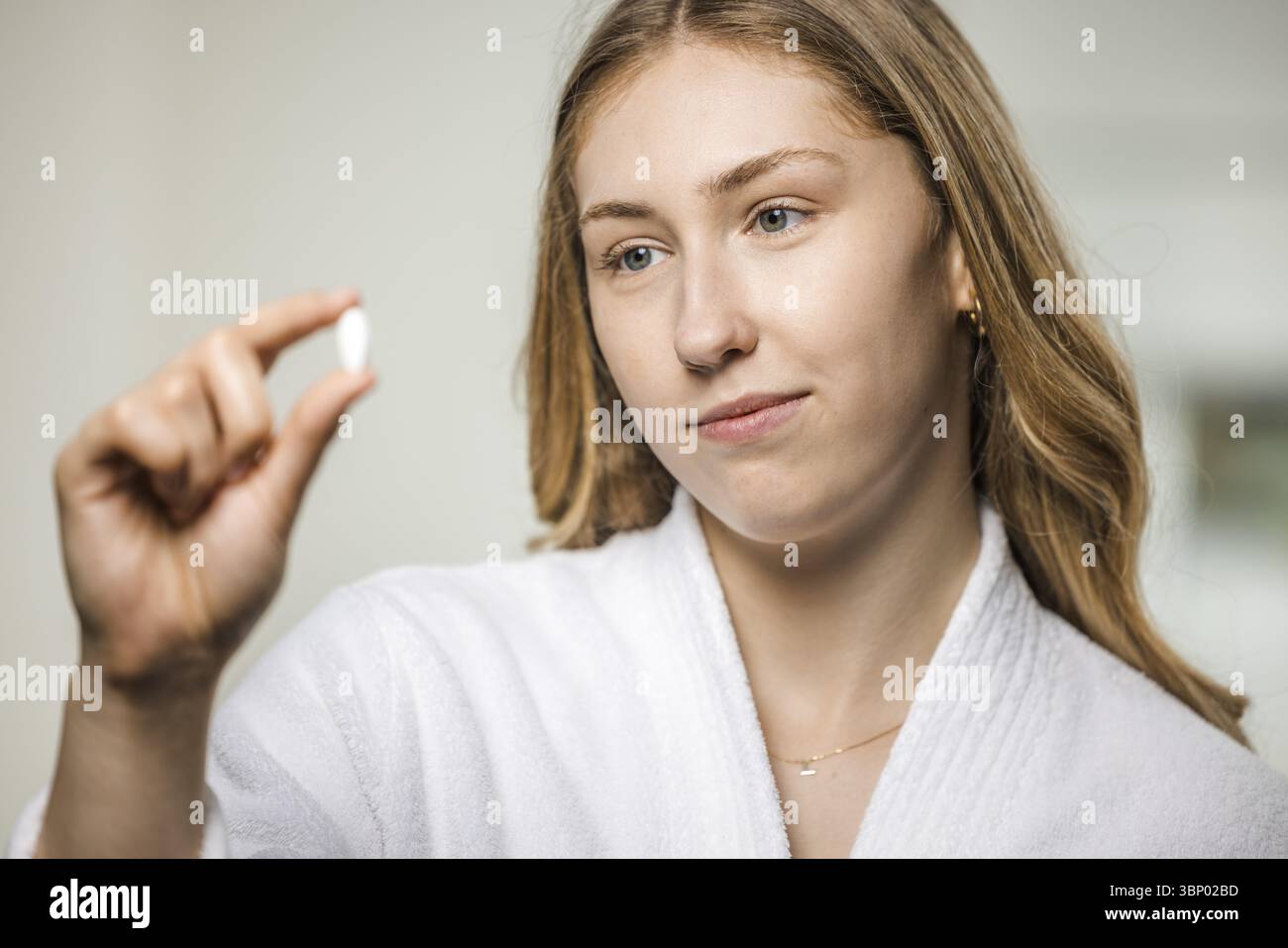 Junge, blonde Frau in einem weißen Bademantel mit Medizin Stockfoto