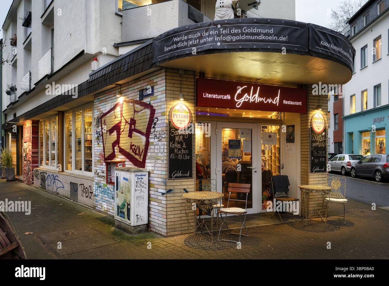 Köln, Deutschland 16. Dezember 2024: Das beleuchtete Literaturcafé und Restaurant Goldmund im Kölner Stadtteil Ehrenfeld in der Abenddämmerung Stockfoto