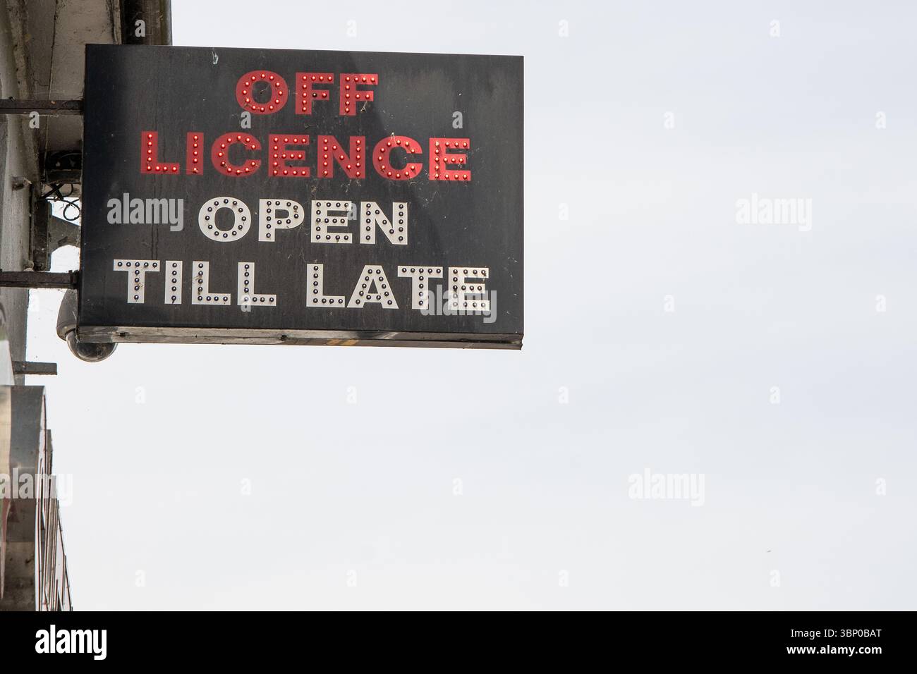 Neon-Ladenschild mit der Aufschrift „Off Licence Open Till Late“ mit rotem und weißem Text. Obwohl beleuchtet, wurde das Foto bei Tageslicht außerhalb des Ladens aufgenommen. Stockfoto