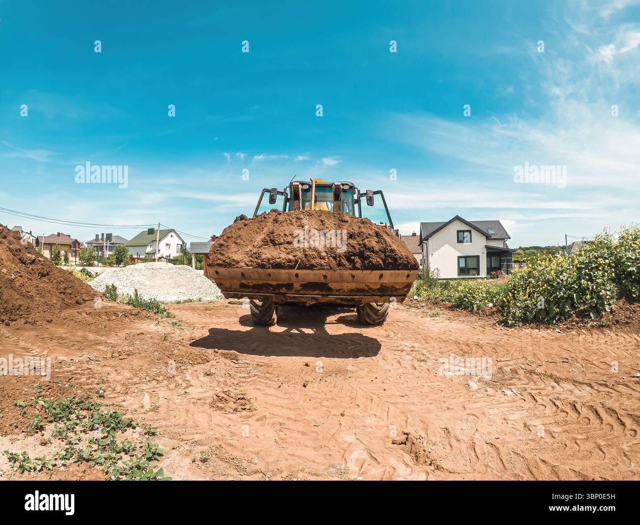 Großer gelber Traktorlader transportiert Erde. Vorbereitung der Baustelle. Landschaft ausgleichen Stockfoto