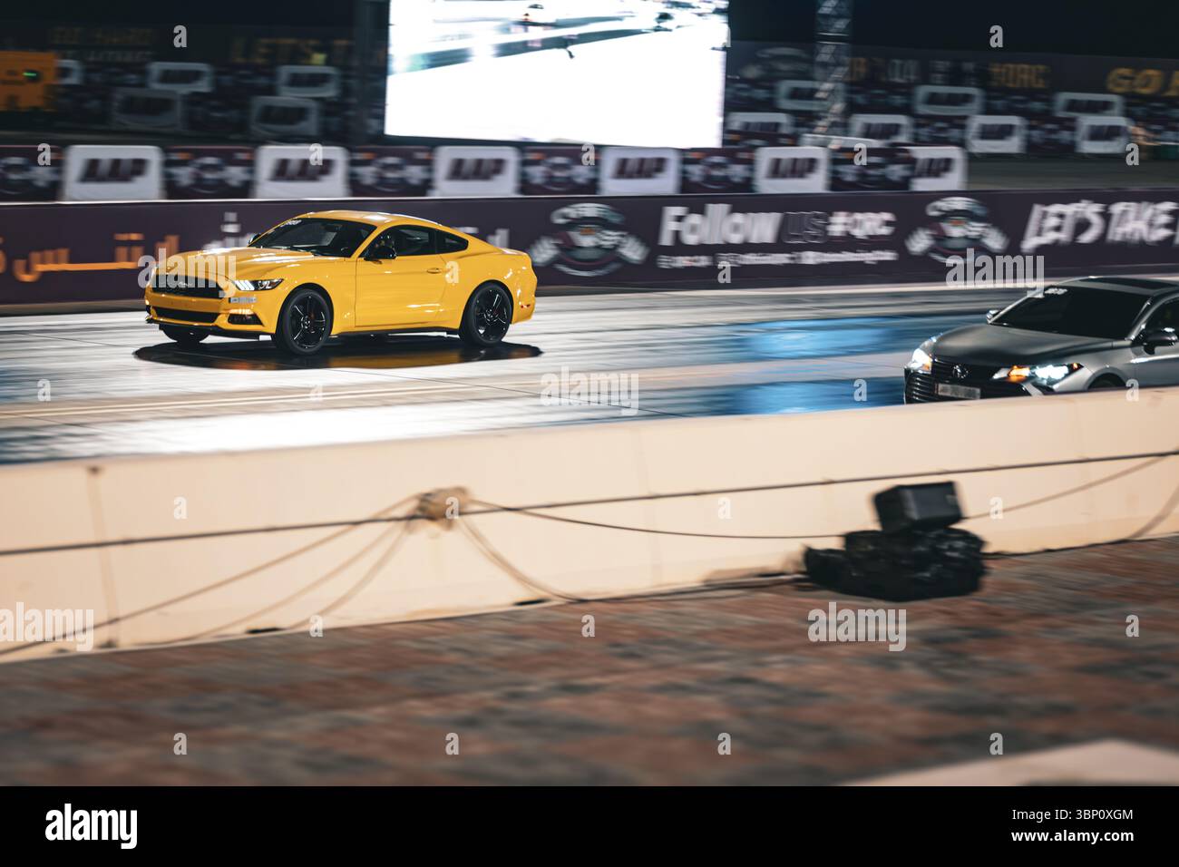 Motion Blur Drag Racing bei Nacht, bei dem Autos auf der Rennstrecke mit Zuschauern in der Nähe konkurrieren Stockfoto