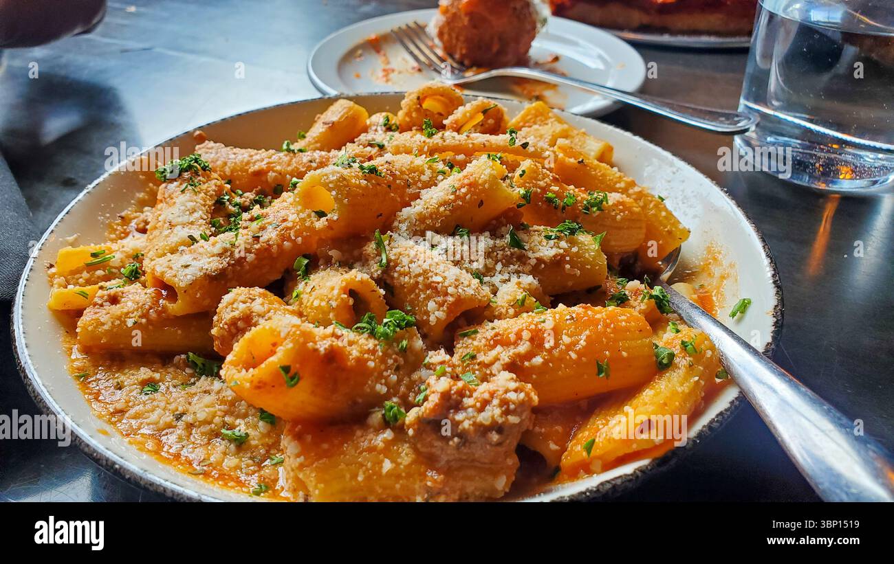 Cremige Rigatoni-Pasta mit Parmesan und Petersilie im Restaurant Stockfoto