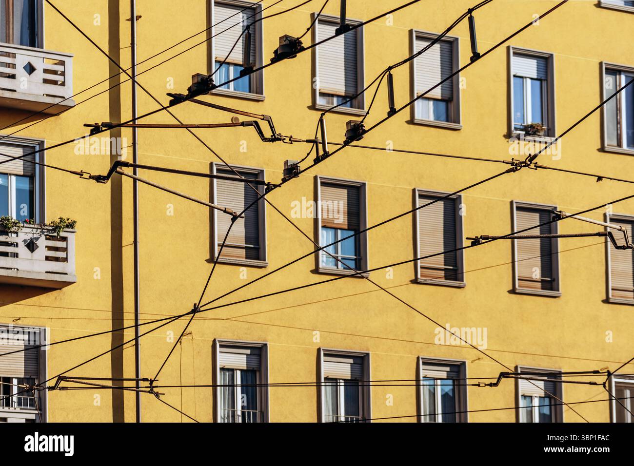 Straßenbahnkabel und gelbe Wohnfassade im Viertel Navigli in Mailand Stockfoto