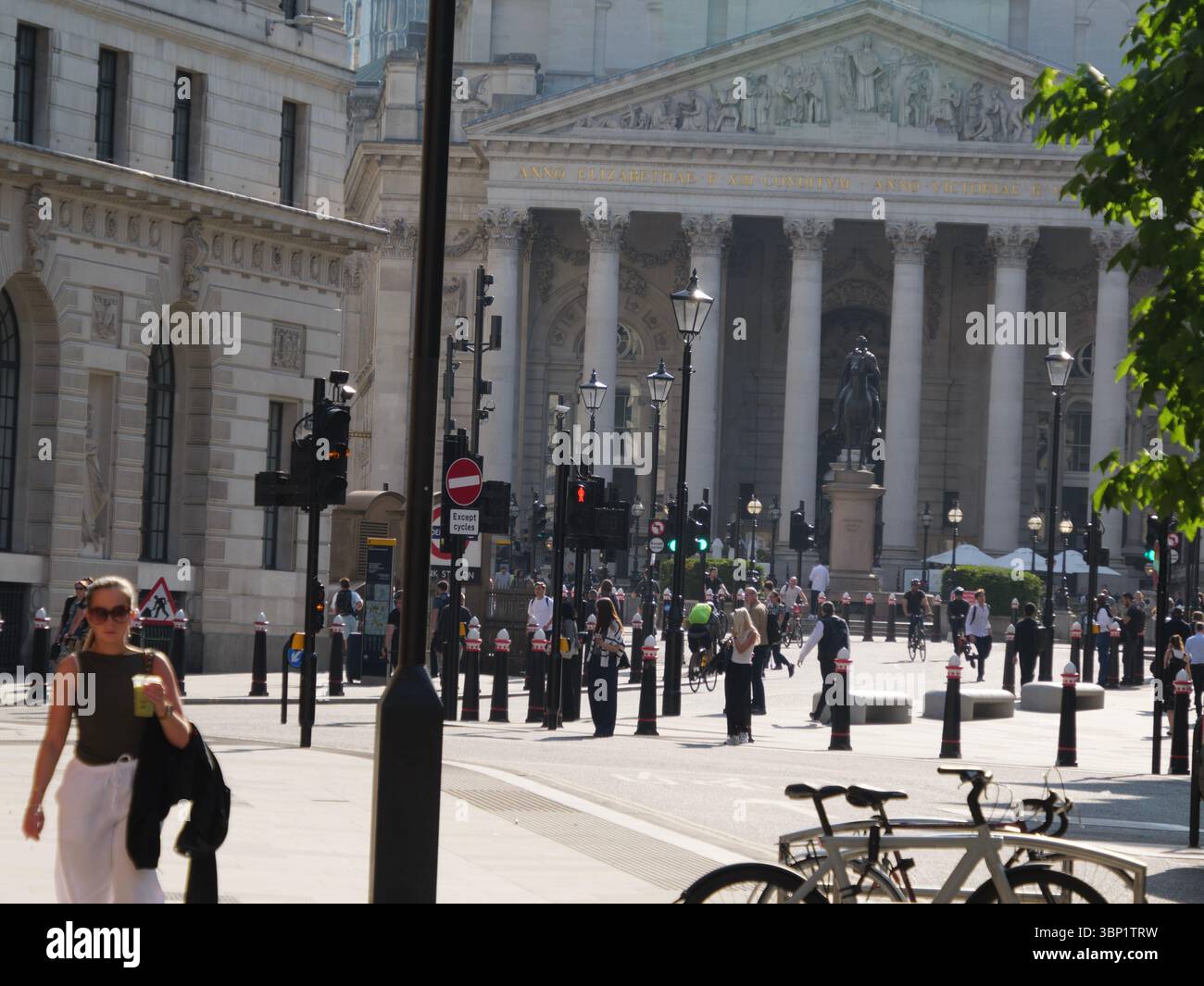 Pendler am frühen Morgen begeben sich während der Hauptverkehrszeit durch das Herz der City of London, mit der historischen Royal Exchange und ihren ikonischen neoklassizistischen Säulen, die eine eindrucksvolle Kulisse bilden Stockfoto