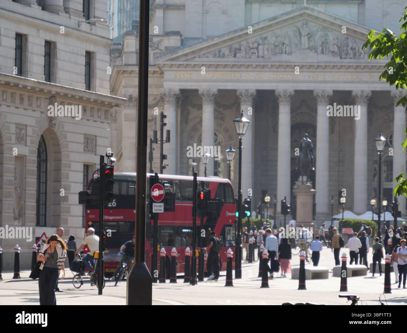 Pendler am frühen Morgen begeben sich während der Hauptverkehrszeit durch das Herz der City of London, mit der historischen Royal Exchange und ihren ikonischen neoklassizistischen Säulen, die eine eindrucksvolle Kulisse bilden Stockfoto