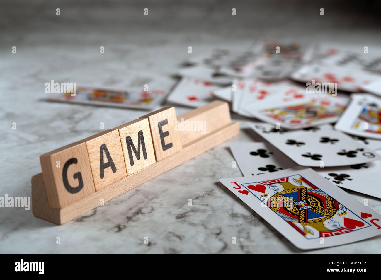 Auf einem Holzgestell befinden sich Briefblöcke mit der Schreibweise „SPIEL“, auf denen Spielkarten auf einer strukturierten Oberfläche verteilt sind Stockfoto