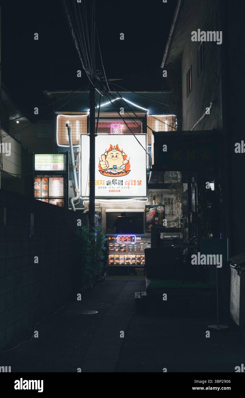 Hell beleuchtetes koreanisches BBQ-Schild beleuchtet nachts eine enge Gasse Stockfoto