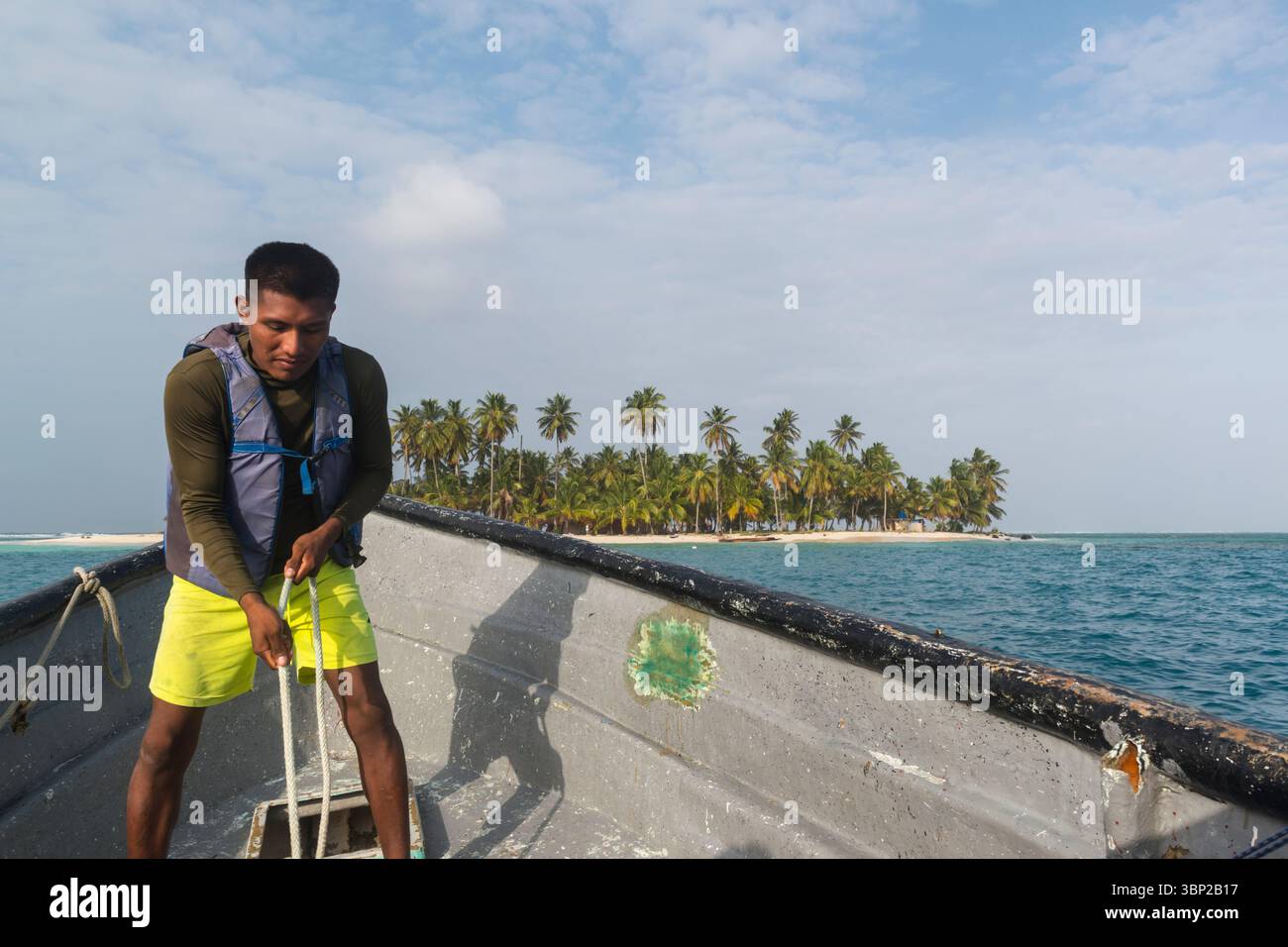 Boatsman hebt den Anker aus dem Laderaum, während das Boot eine Insel im San Blas Archipel in Panama erreicht. Stockfoto