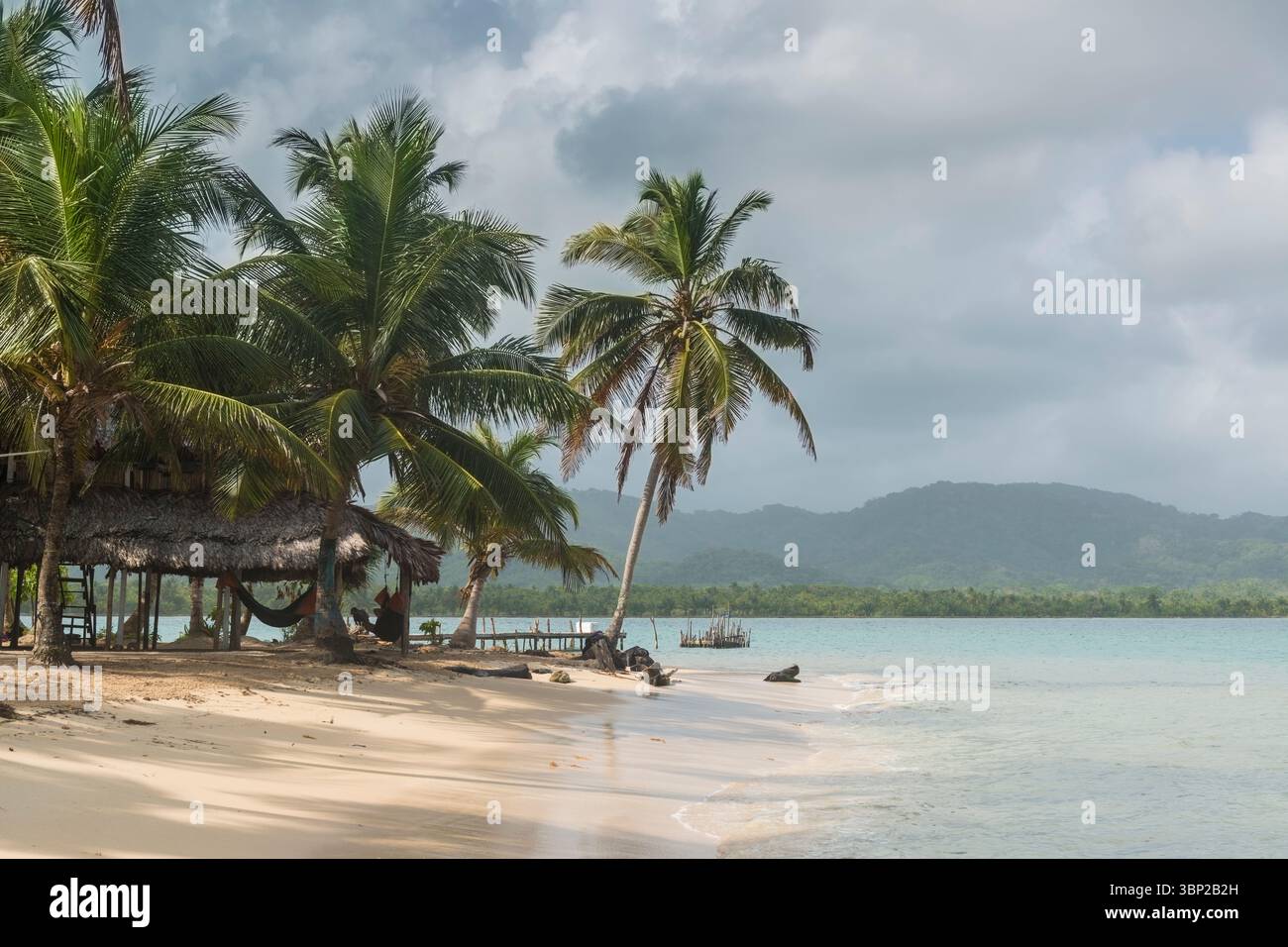 Hängematten unter einem Baldachin und einem kleinen hölzernen Dock auf einer Insel im San Blas Archipel. Im Hintergrund der grüne Dschungel der Darien Gap, Panama Stockfoto