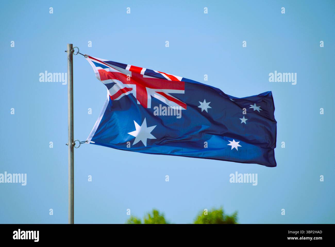 Die Nationalflagge Australiens fliegt stolz an einem wunderschönen Sommertag mit blauem Himmel auf einem Fahnenmast. Stockfoto