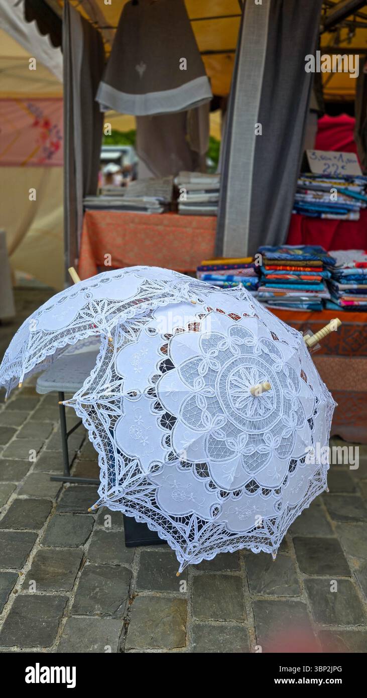 Zwei offene Sonnenschirme aus weißer Spitze auf dem Bürgersteig, auf dem Straßenmarkt. Vertikales Format Stockfoto