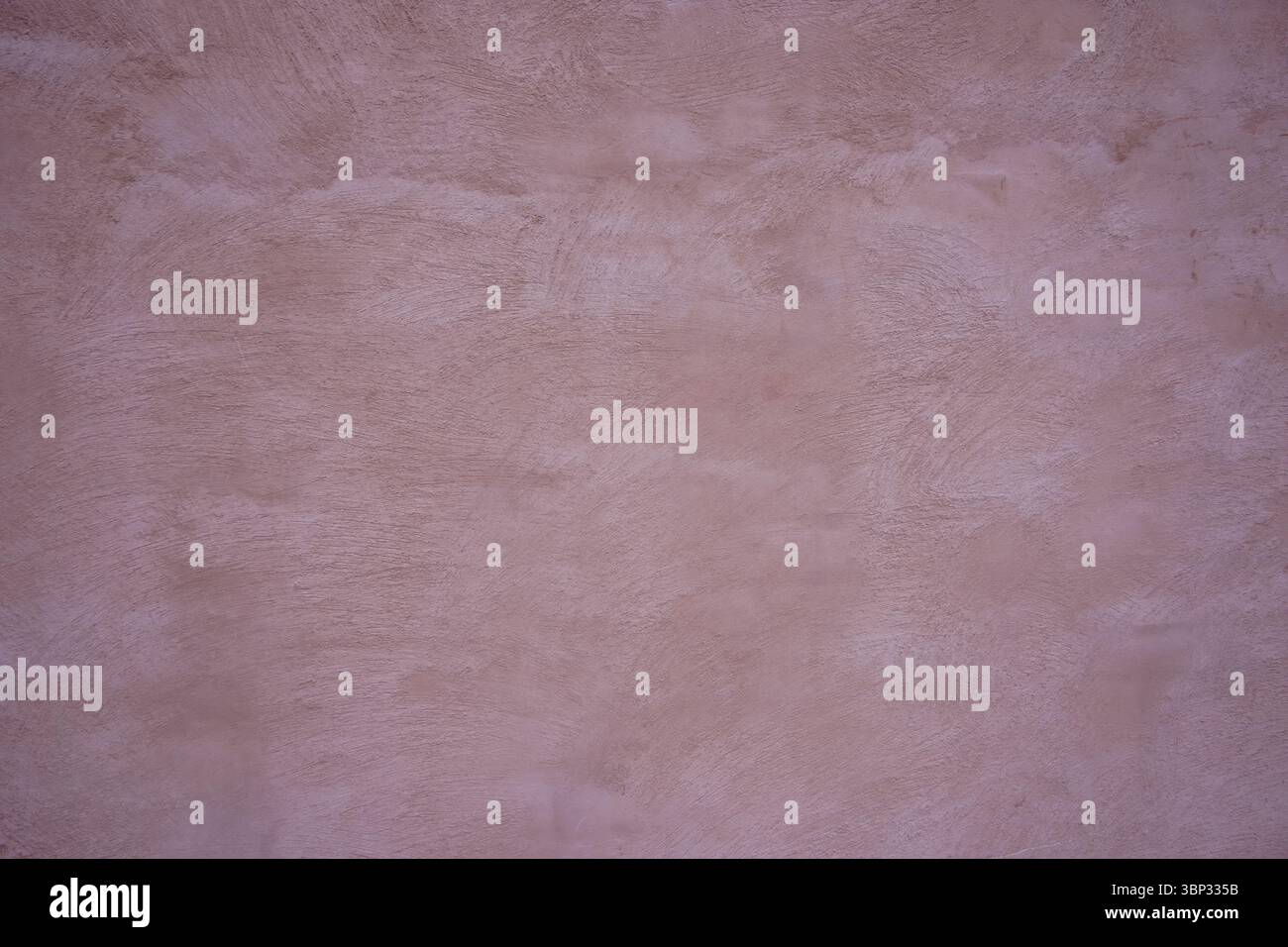 Eine glatte Wand mit einem dezenten rosafarbenen Farbton, beleuchtet durch natürliches Licht, schafft ein warmes Ambiente. Die Textur verleiht dem Innenbereich Tiefe und Interesse Stockfoto