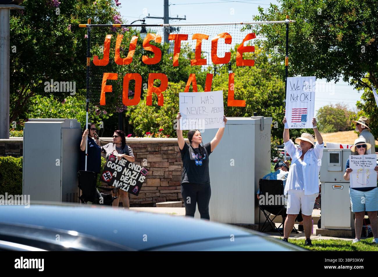 Ein Aktivist hält ein Schild, das besagt, dass es nie um den Rechtsstatus ging, vor einem „Justice for All“-Zeichen bei einem Protest am 4. Juli in der Nähe der Westfield Galleria Stockfoto