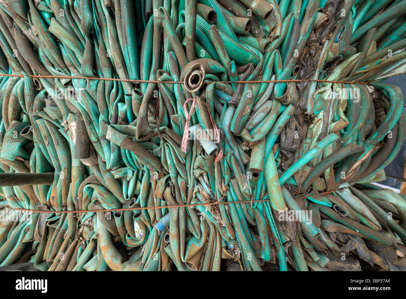 Nan, Thailand - 8. Juni 2025 - abstrakte Textur alter, grüner Gartenschläuche aus Kunststoff, die für das industrielle Recycling komprimiert und gepresst werden. Diese hohe Stockfoto