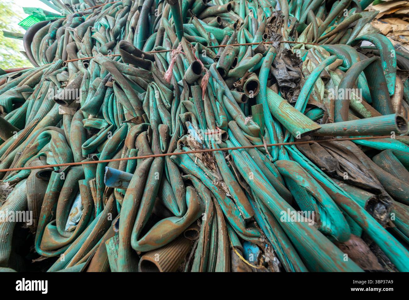 Nan, Thailand - 8. Juni 2025 - abstrakte Textur alter, grüner Gartenschläuche aus Kunststoff, die für das industrielle Recycling komprimiert und gepresst werden. Diese hohe Stockfoto