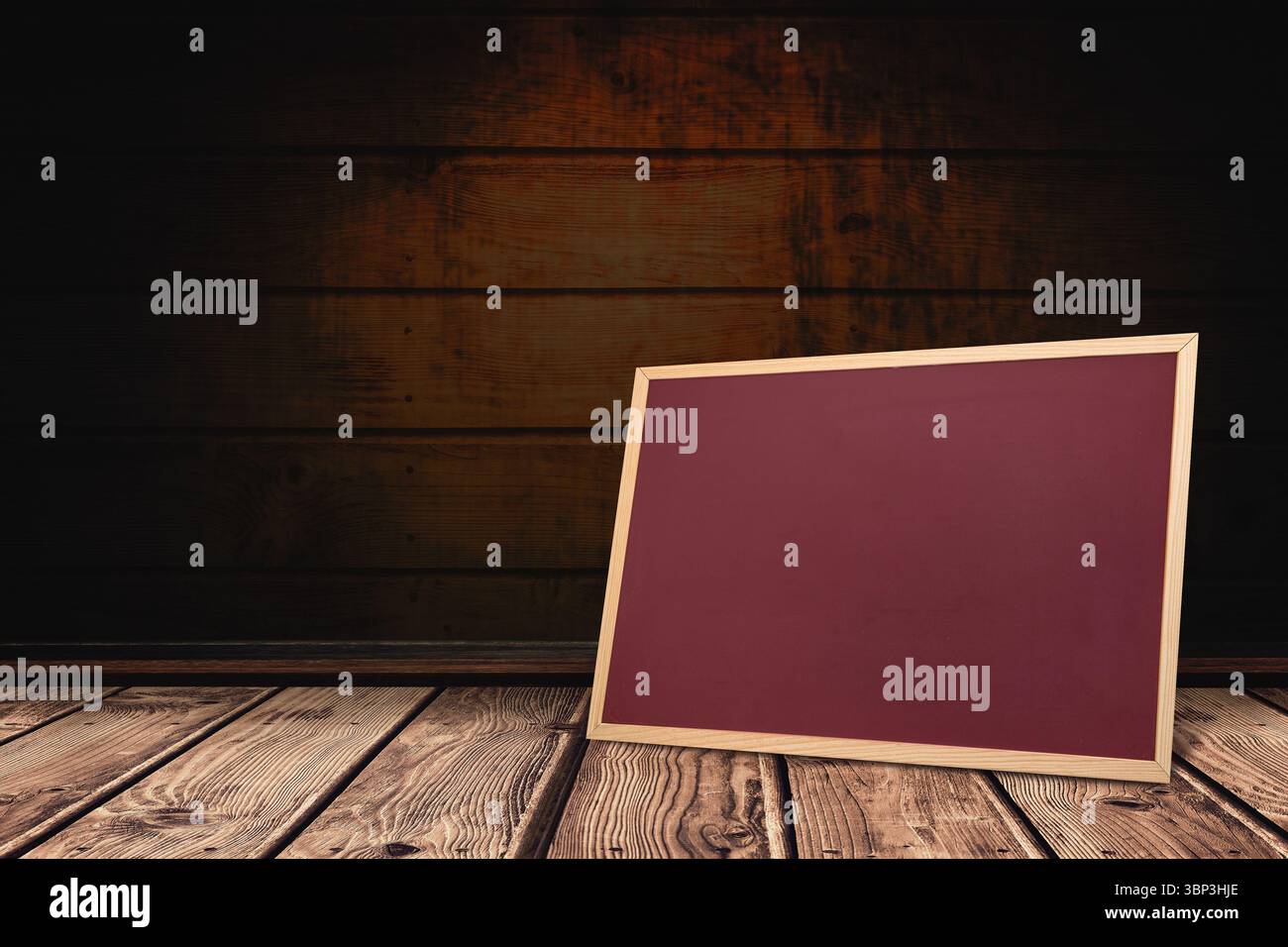 Leere, mit Holzrahmen versehene Kreidetafel, die sich an dunkle Wand und Boden der Diele in flacher Ausführung anlehnt Stockfoto