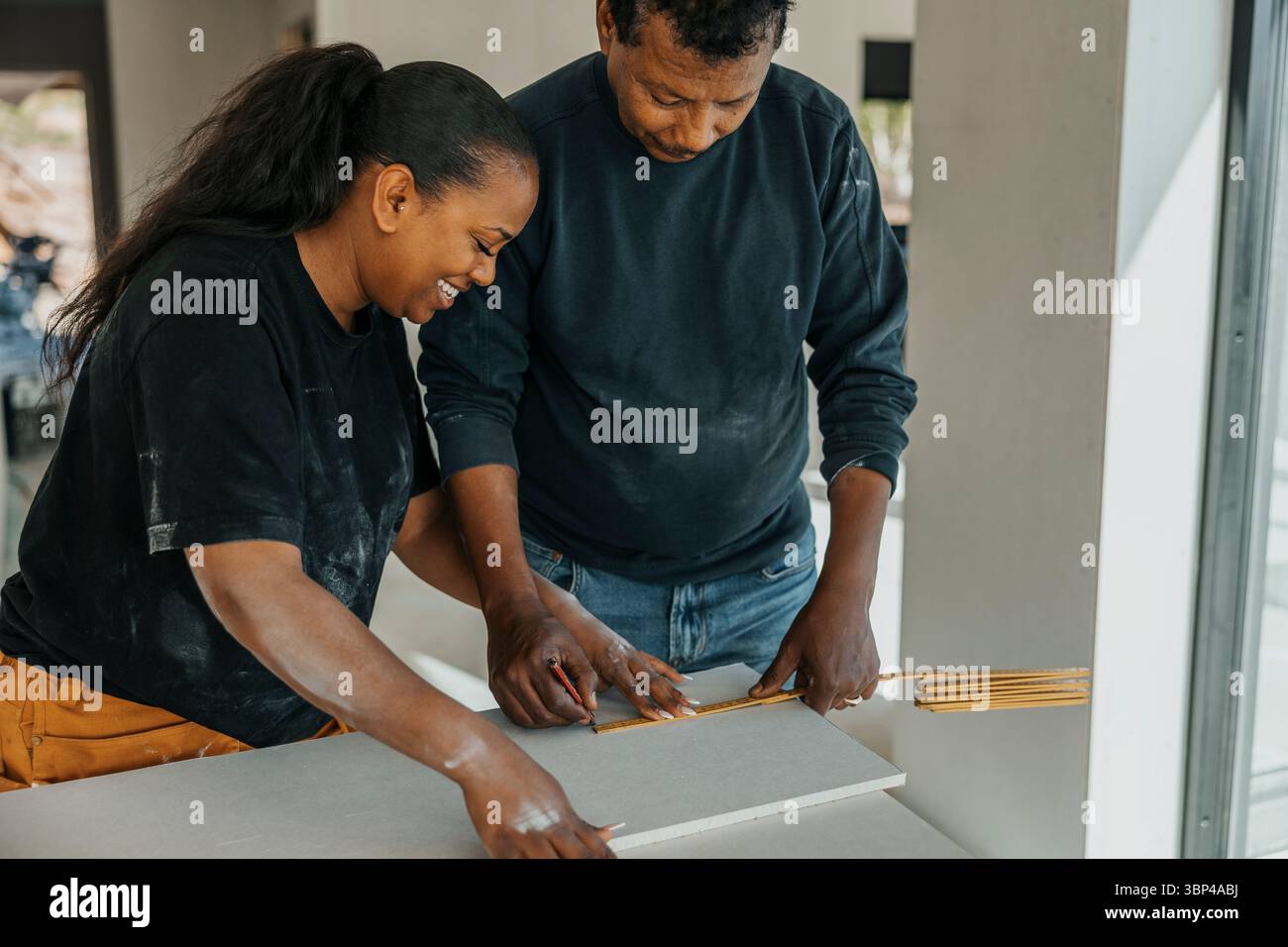 Männliche und weibliche Bauarbeiter messen Holzdielen auf der Baustelle Stockfoto