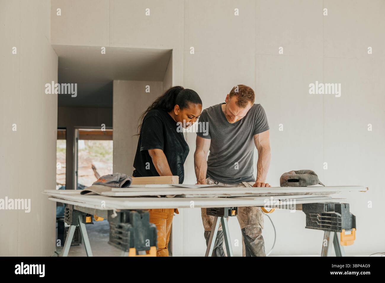 Multirassisches Paar diskutiert Hausverbesserungsplan auf der Baustelle Stockfoto