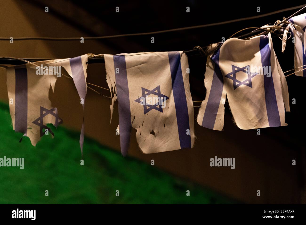 Eine Reihe kleiner, zerrissener und zerrissener israelischer Flaggen hing an einer Linie, um die Feiertage der Gedenkfeier und der Unabhängigkeitstage in Israel zu markieren. Stockfoto