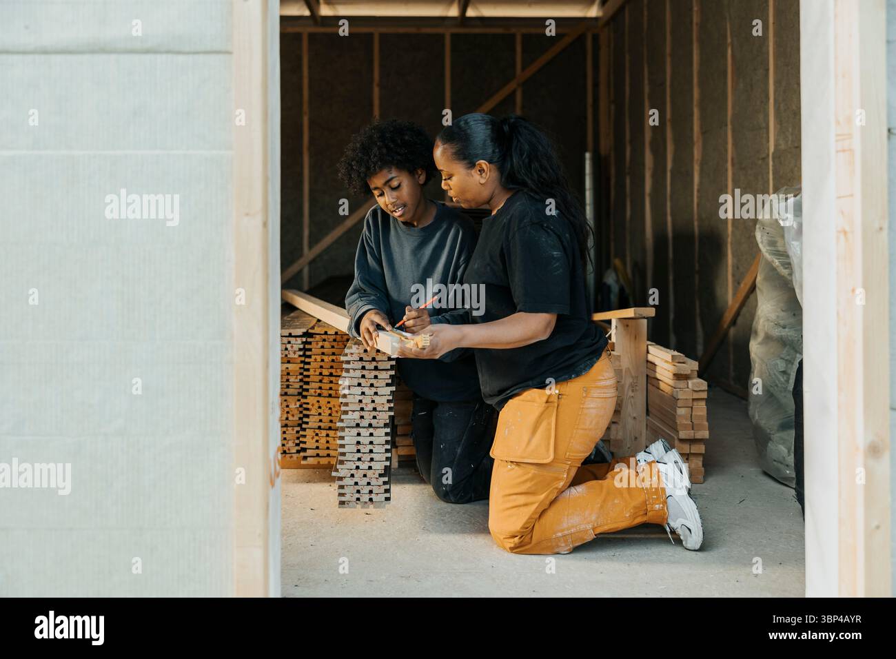 Bogenmarkierungsmessung auf Holzplanken mit Hilfe der Mutter auf der Sanierungsstelle Stockfoto