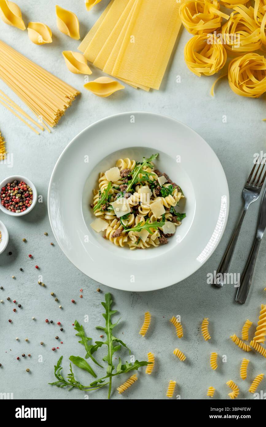 Leckere Pasta serviert mit Rucola und Käse auf einem weißen Teller Stockfoto