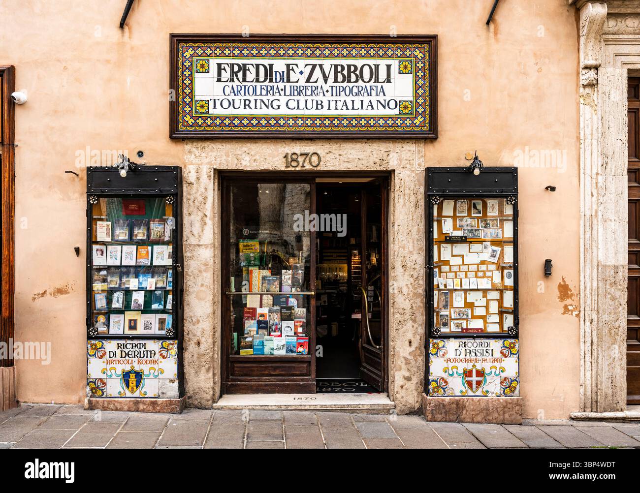 Fassade des historischen Zubboli Buchhandels und Druckhauses, 1870 auf der Piazza del Comune, im Herzen der mittelalterlichen Altstadt von Assisi, Umbrien, Italien. Stockfoto