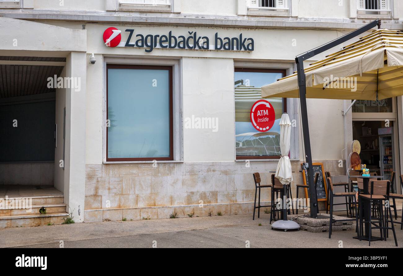 Porec, Kroatien - 21. Mai 2025: Die Bankfiliale in Zagreb verfügt über ein großes Fenster mit einem Schild im Inneren des Geldautomaten, das sich neben einer kleinen Gelateria mit Sitzplatz im Freien befindet Stockfoto