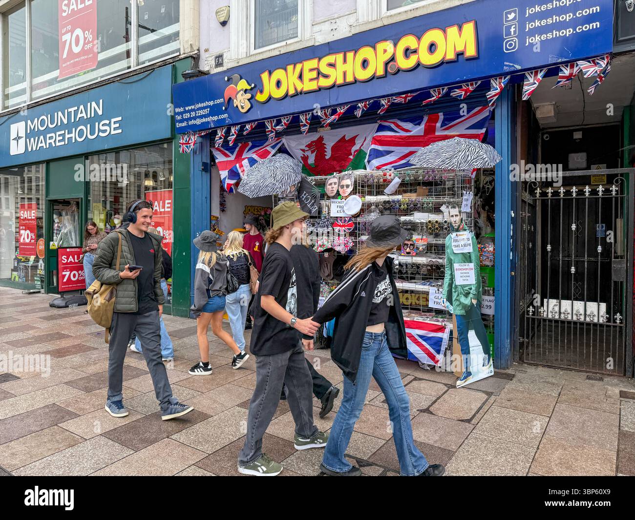 Oasis Tour Cardiff Concert Fans tragen Band T-Shirts und Merchandise vor Jokeshop - Smartphone-aufgenommenes Stockfoto