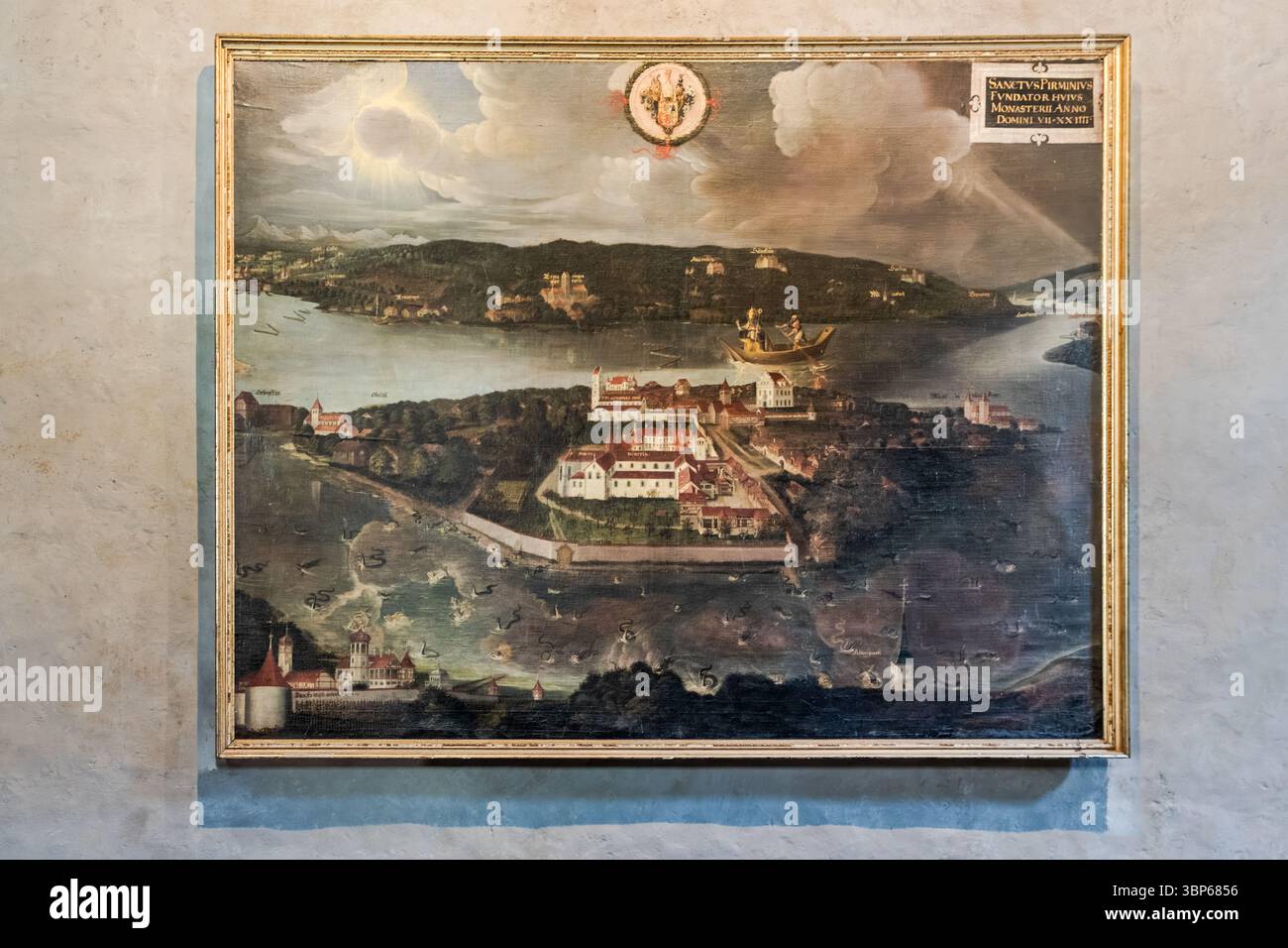 Ein Tafelbild aus dem Jahr 1624 in der St. Maria und St. Markus Domkirche auf der Reichenau, Baden-Württemberg, Deutschland, zeigt die Gründungslegende der Insel: die Ankunft des heiligen Pirmin im Jahr 724. Im Mittelpunkt steht der ummauerte Klosterkomplex mit dem Abtspalast, der im 19. Jahrhundert abgerissen wurde, und der Pfarrkirche St. Johann. Das 'Hohe Haus' liegt am Hafen, die Ruinen von Schopflen und die Kirche St. Georg in Oberzell erscheinen am linken Rand, und St. Peter und Paul in Niederzell auf der rechten Seite. Stockfoto