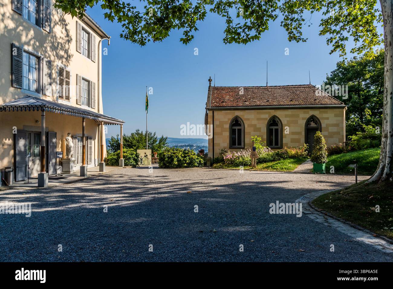 Das Bild zeigt das historische Schloss Arenenberg in Salenstein, Thurgau, Schweiz, eine ehemalige Residenz von Hortense de Beauharnais und Napoleon III. Heute beherbergt es das Napoleon Museum Thurgau. Sie können die Hauptgebäude des Anwesens mit ihren charakteristischen Fassaden und Fenstern sehen, umgeben von der gepflegten Anlage und einem Schotterplatz. Der Ort bietet einen malerischen Blick auf die umliegende Landschaft und den Bodensee, was seine Bedeutung als kulturelles und historisches Zentrum unterstreicht Stockfoto