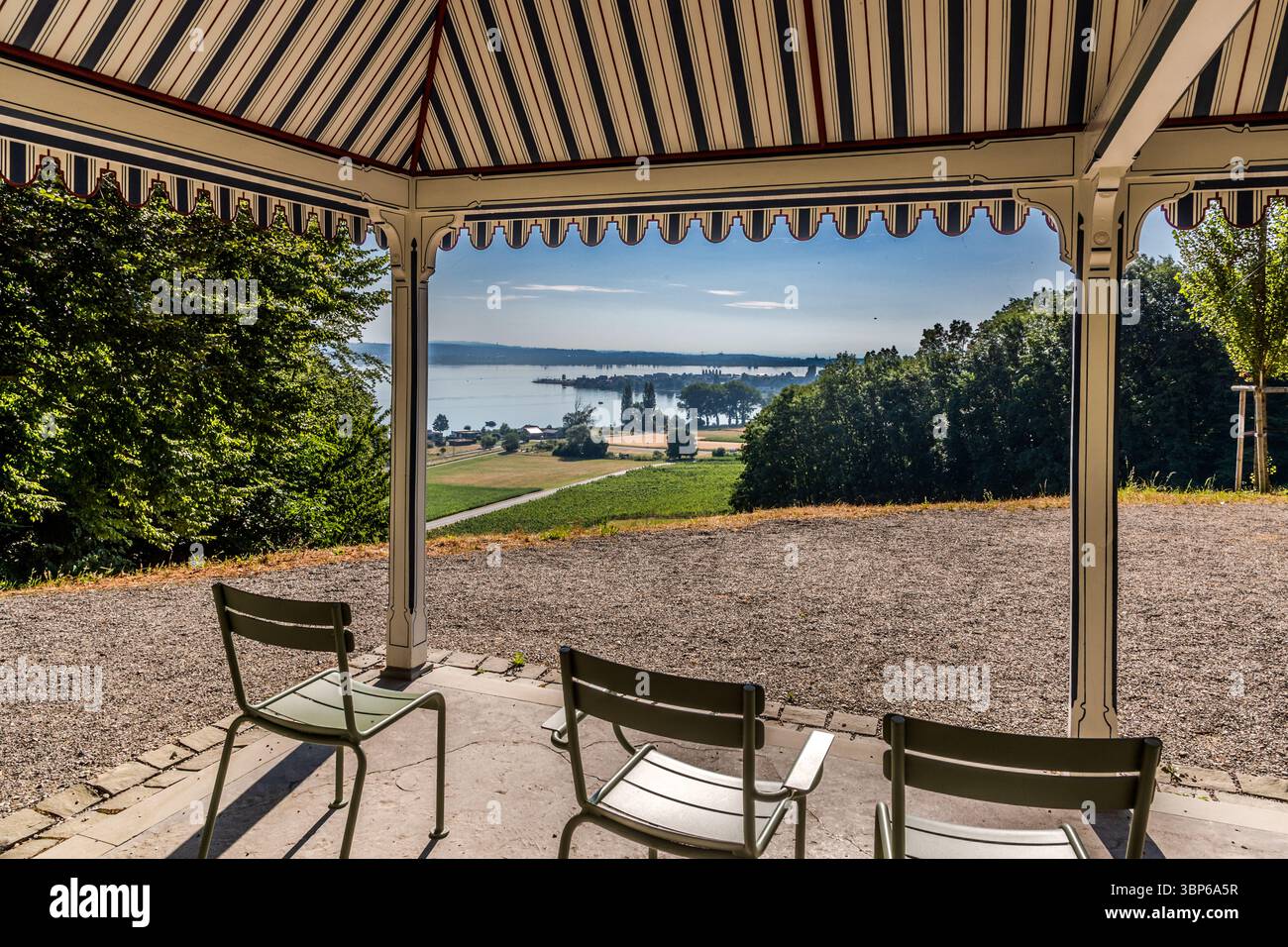 Blick vom Pavillon am Arenenberg in Salenstein, Thurgau, Schweiz. Sie können die Unterläufe des Bodensees sehen, umgeben von Feldern und Bäumen. Drei Stühle laden zum Verweilen ein und genießen die malerische Aussicht Stockfoto