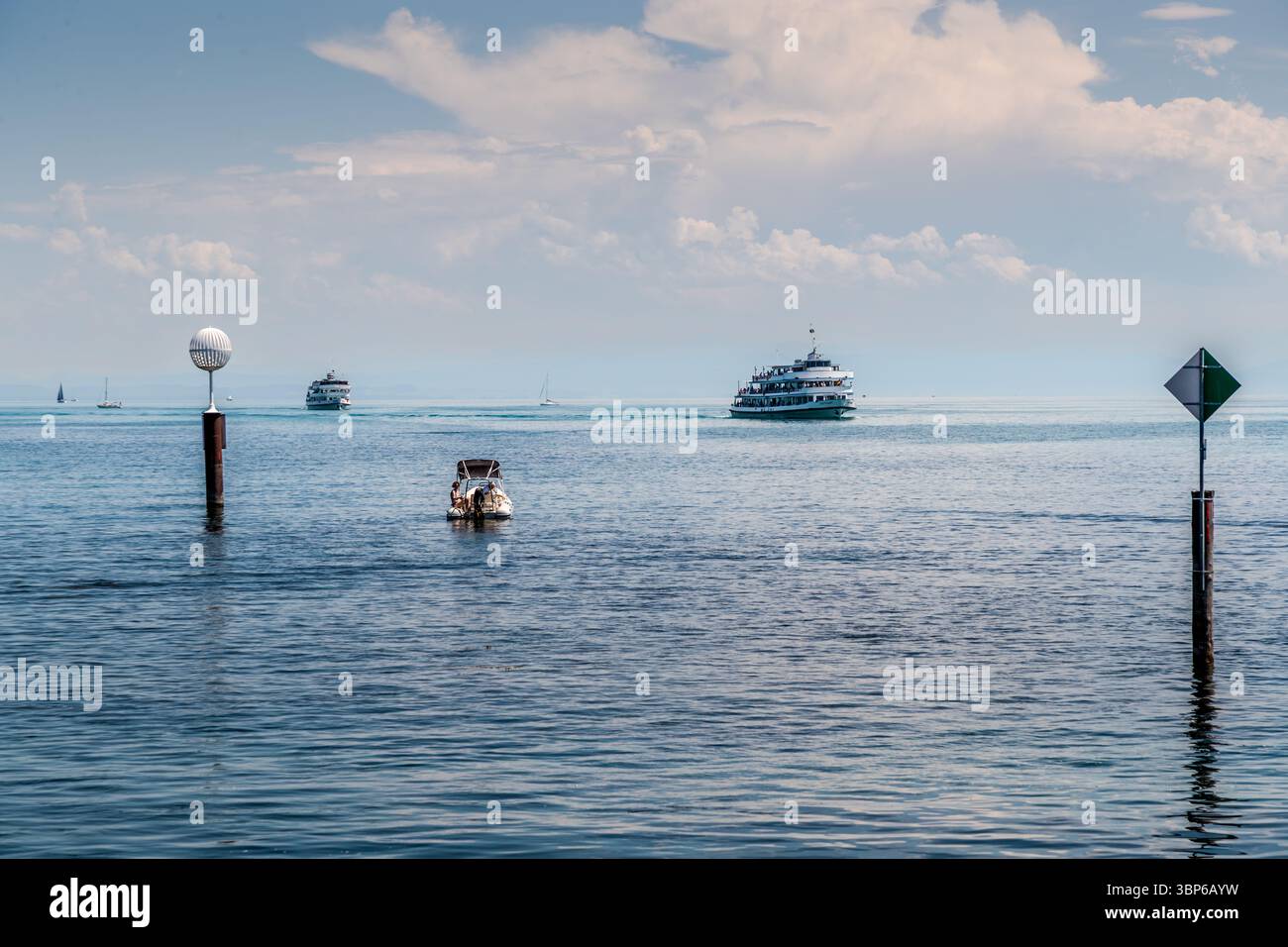 Ein Motorboot mit zwei Personen fährt auf dem Bodensee. Zwei Passagierschiffe und mehrere Segelboote befinden sich ebenfalls auf dem Wasser. Konstanz, Baden-Württemberg, Deutschland Stockfoto