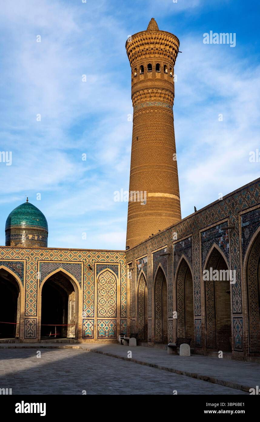 Ein atemberaubender Blick auf einen alten architektonischen Komplex mit einem hohen Minarett und aufwändig gekachelten Gebäuden. Der Himmel ist hell mit weichen Wolken, enha Stockfoto