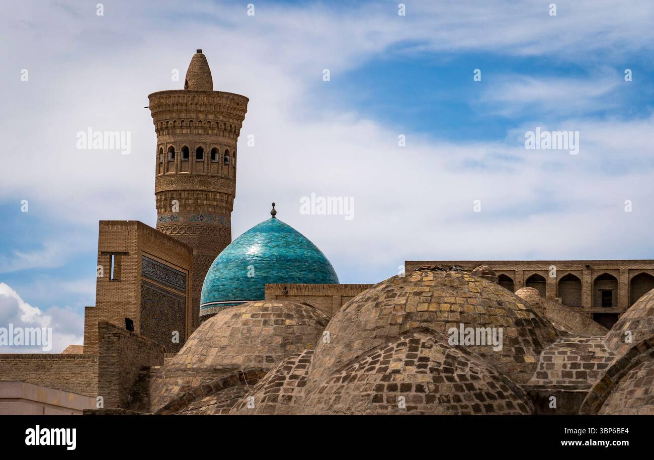 Ein malerischer Blick auf die antike Architektur mit einer türkisfarbenen Kuppel und einem hohen Minarett vor einem bewölkten Himmel. Der Vordergrund zeigt gewölbte Strukturen, hoch Stockfoto