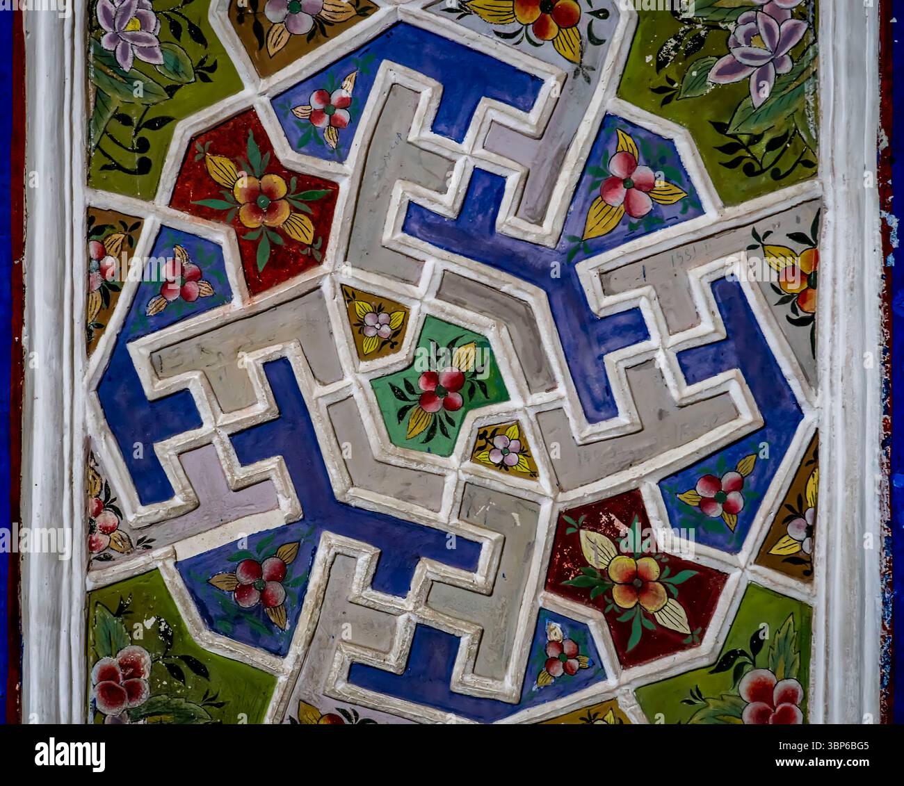 Ein lebendiges, kompliziertes geometrisches Muster mit Blumenmustern in verschiedenen Farben, darunter Blau, Grün, Rot und weiß. Die Grafik zeigt eine Mischung Stockfoto