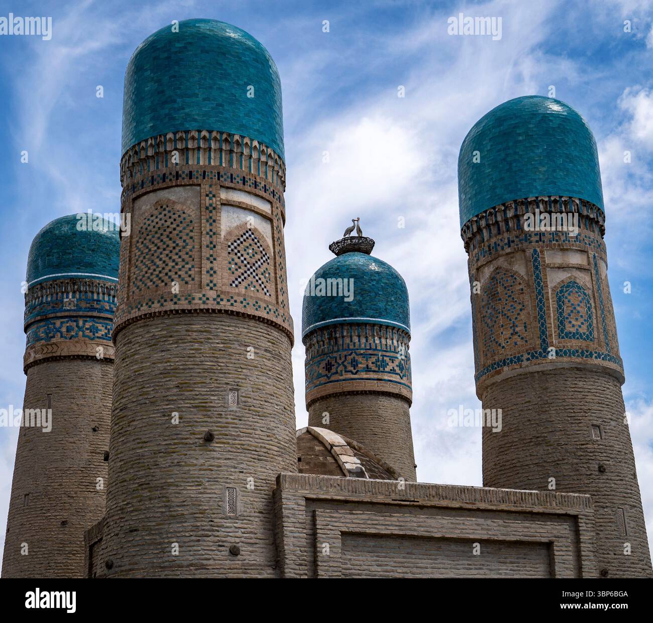 Vier hoch aufragende Minarette mit türkisfarbenen Kuppeln vor blauem Himmel, die komplexe Muster und Texturen zeigen, die historische Architektur widerspiegeln. Stockfoto