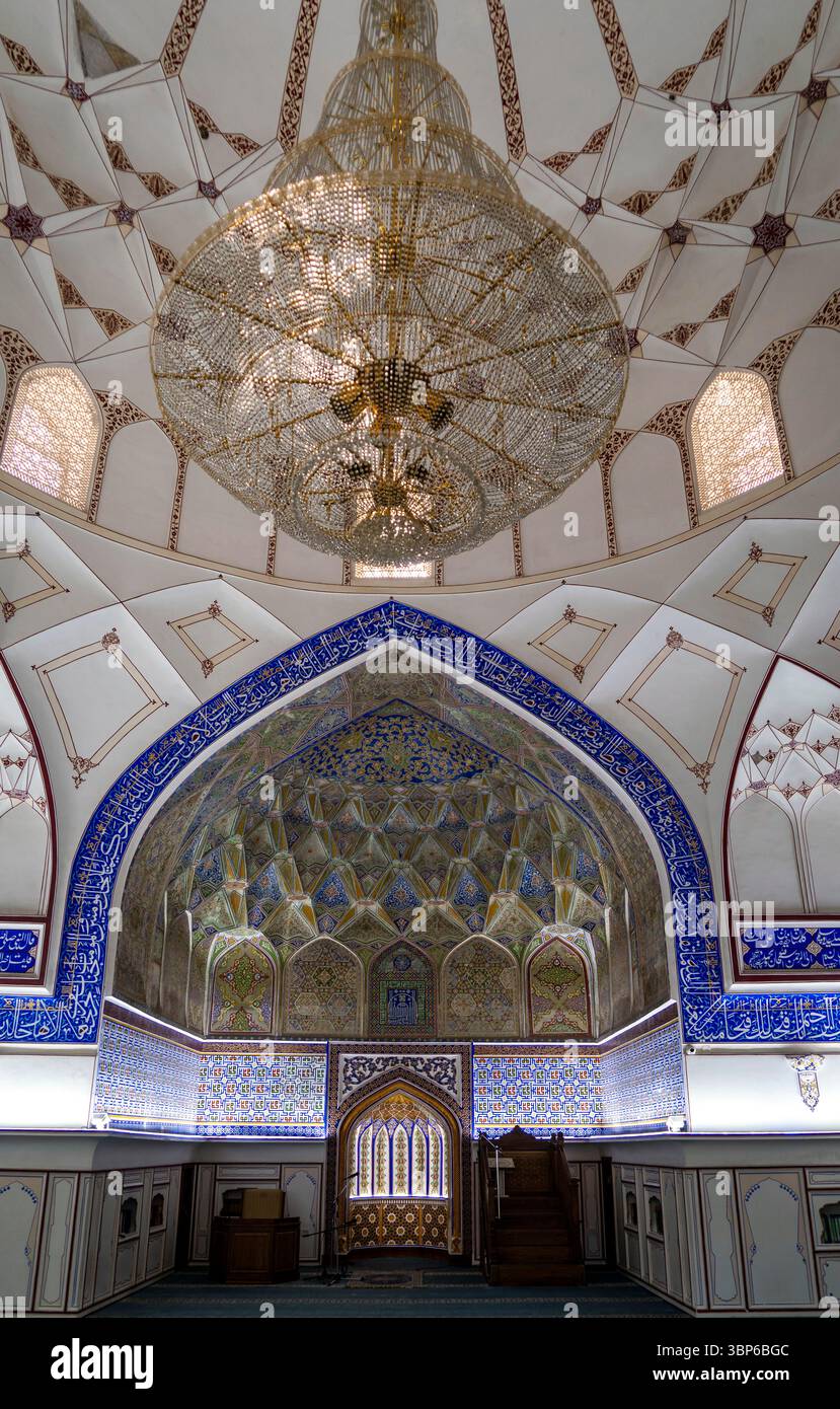 Ein kunstvoll verziertes Innere einer Moschee mit komplizierten Fliesen, einem großen Kronleuchter und wunderschön gestalteten Bögen. An der Decke sind detaillierte Muster zu sehen Stockfoto