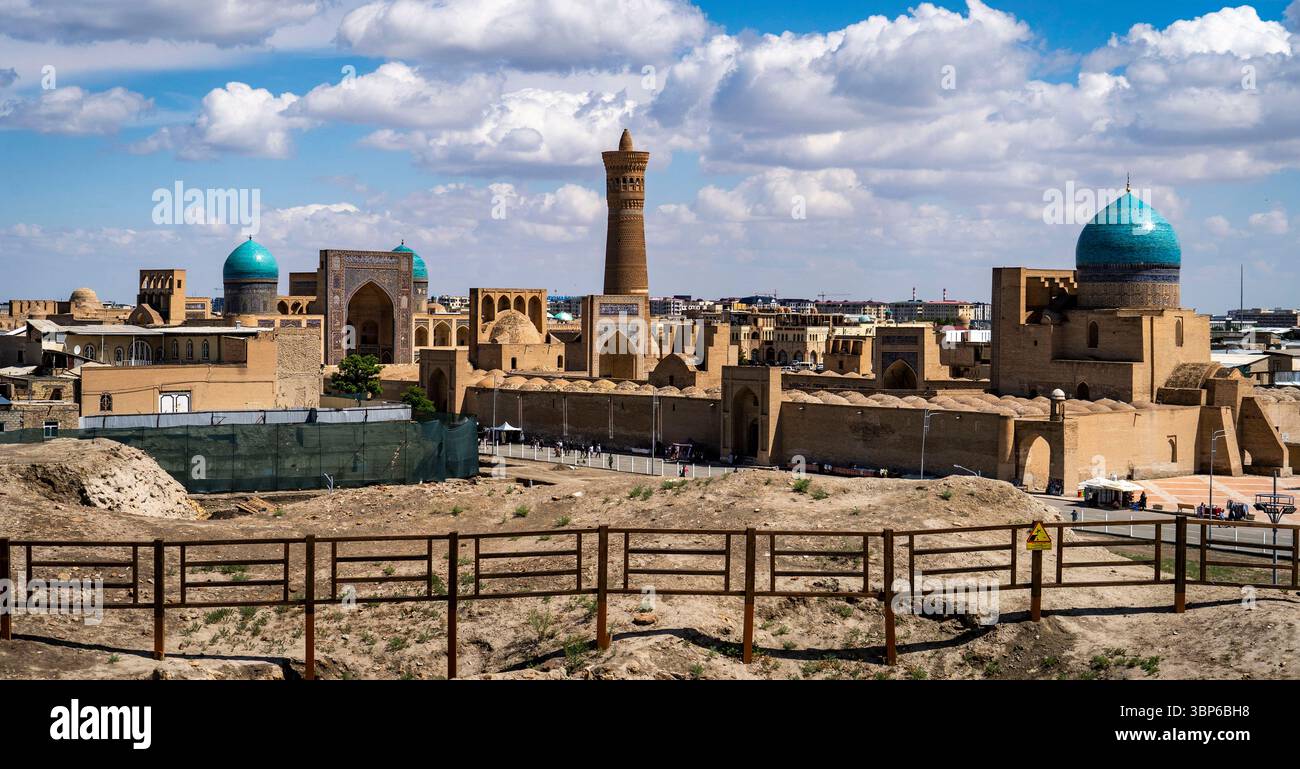 Ein Panoramablick auf die antike Architektur in einer historischen Stadt mit Kuppelbauten und einem hohen Minarett unter einem blauen Himmel mit flauschigen Wolken. Stockfoto