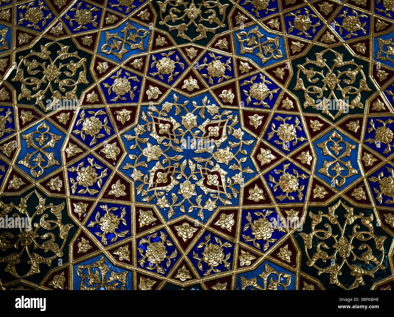 Ein lebendiges und kompliziertes geometrisches Muster in Blau-, Gold- und kastanienbraunen Farben. Das Design zeigt detaillierte Blumen- und Sternmotive, die ein Me kreieren Stockfoto