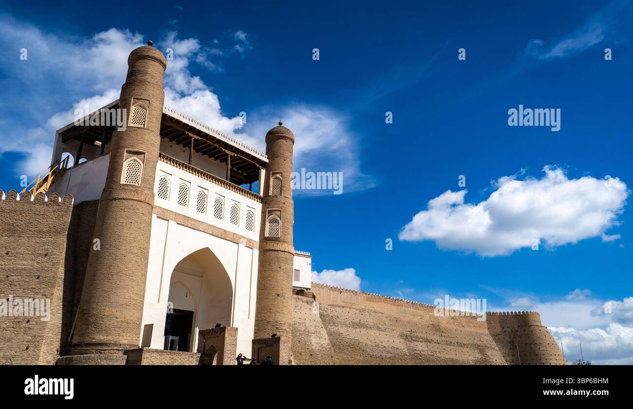 Eine historische Festung mit hohen Türmen und einem großen Bogengang vor einem hellblauen Himmel mit flauschigen weißen Wolken. Die Struktur weist einen komplizierten Bogen auf Stockfoto