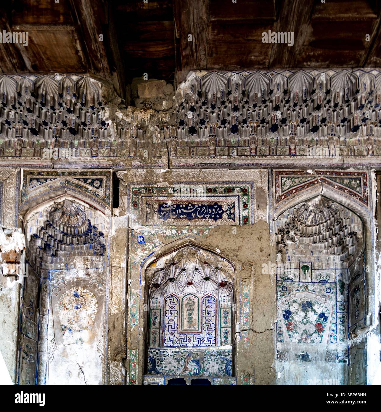Eine aufwändig gestaltete Mauer mit verblassten Fresken und kunstvollen Bögen, die historische Architektur zeigt. Die Texturen zeigen Alter und Verfall, Highlightin Stockfoto