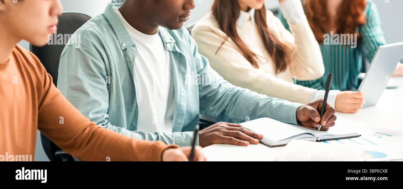 Verschiedene Studenten Sitzen Am Schreibtisch In Der Reihe Und Nehmen Notizen Stockfoto