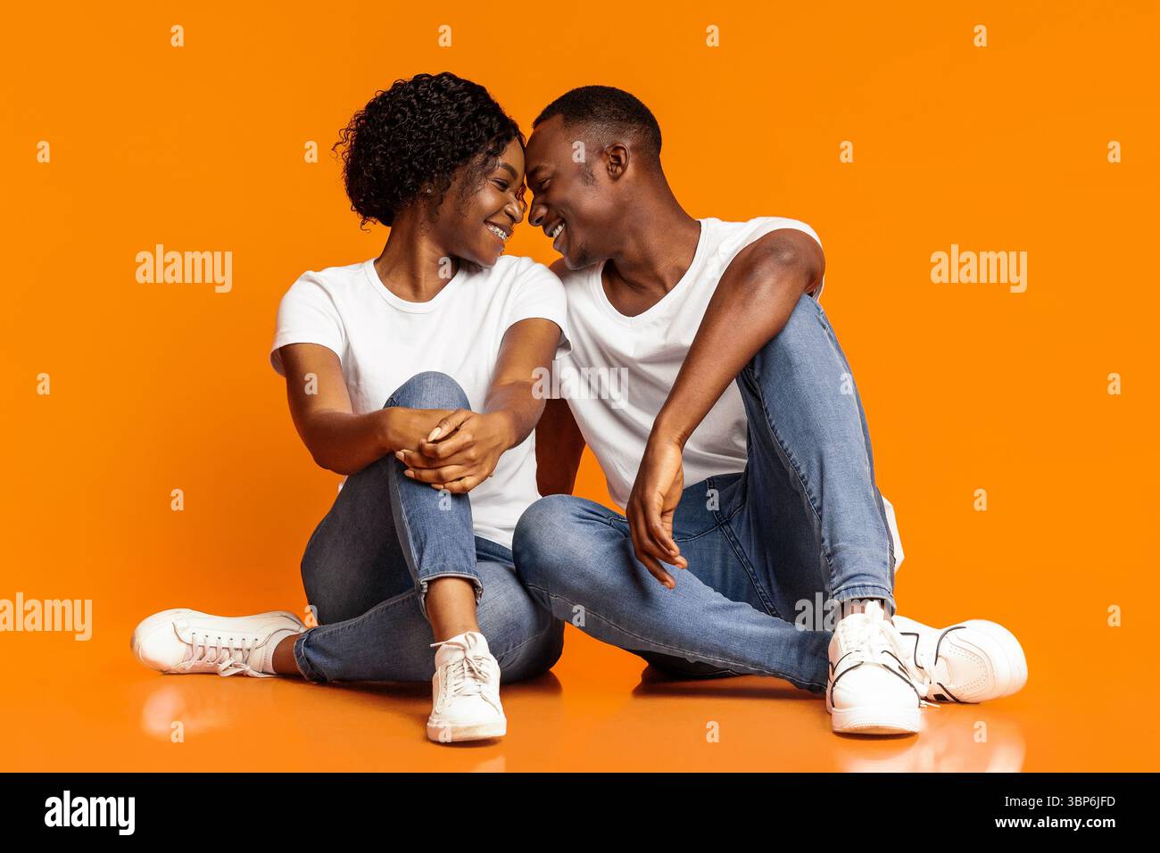 Emotionale schwarze Liebhaber kuscheln auf orangefarbenem Hintergrund Stockfoto