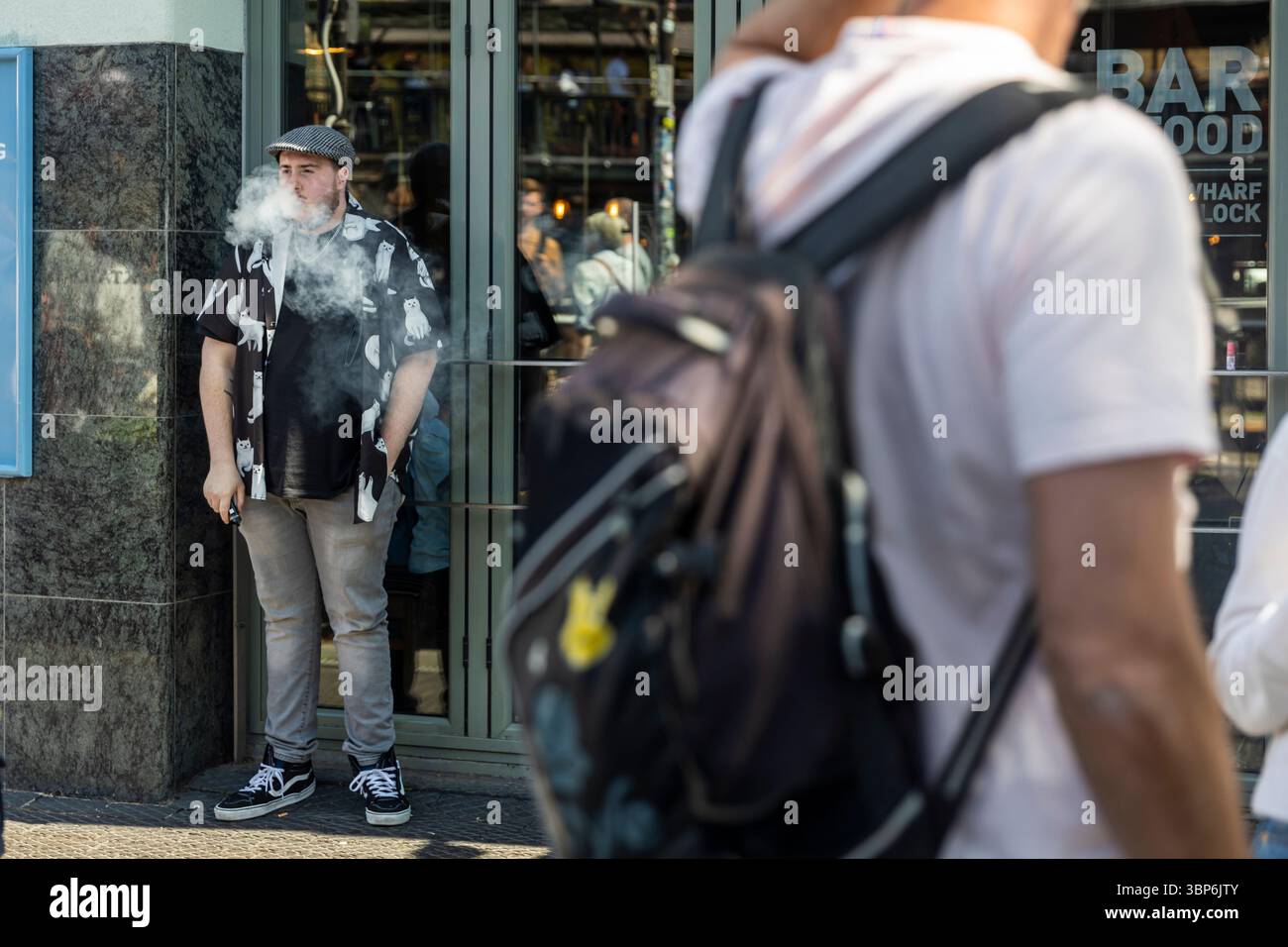 London, Großbritannien, 9. Mai 2025 Ein junger Mann, der auf einer City Street dampft. Stockfoto